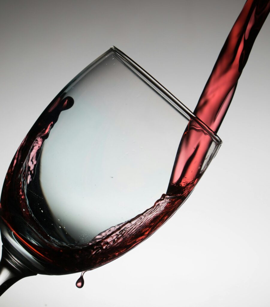 Dramatic capture of red wine being poured into a tilted glass, showcasing elegance and flow.